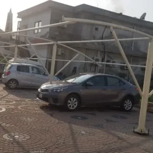 Tensile fabric Car Parking Shed in Pakistan to protect vehicles from sun and rain protection with an elegant look. Image showing Work in Process Shed Structure.